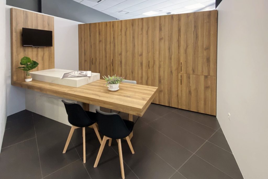 Vista lateral da cozinha com portas de madeira fechadas e península com mesa de jantar e cadeiras.