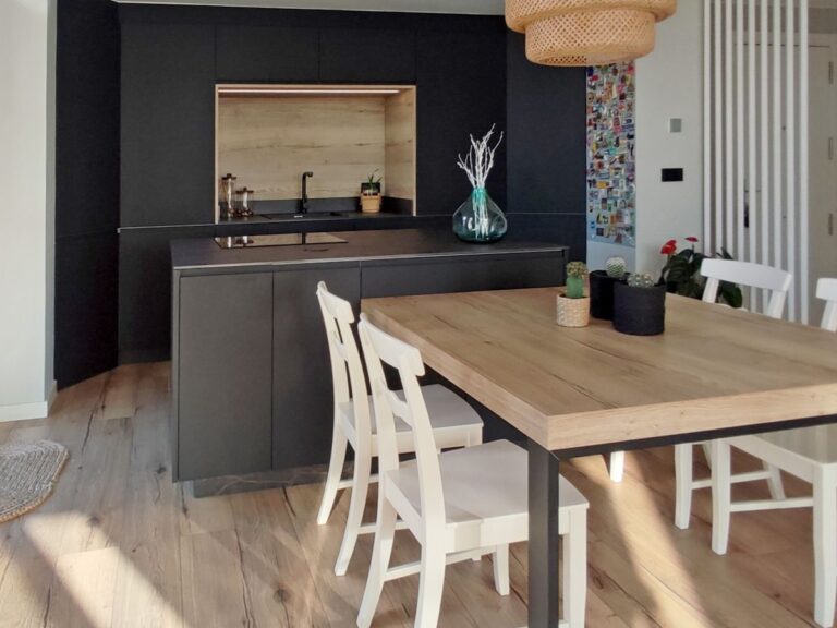Vista lateral de pequeña cocina con el mobiliario en negro y detalles en madera, con isla negra con pla