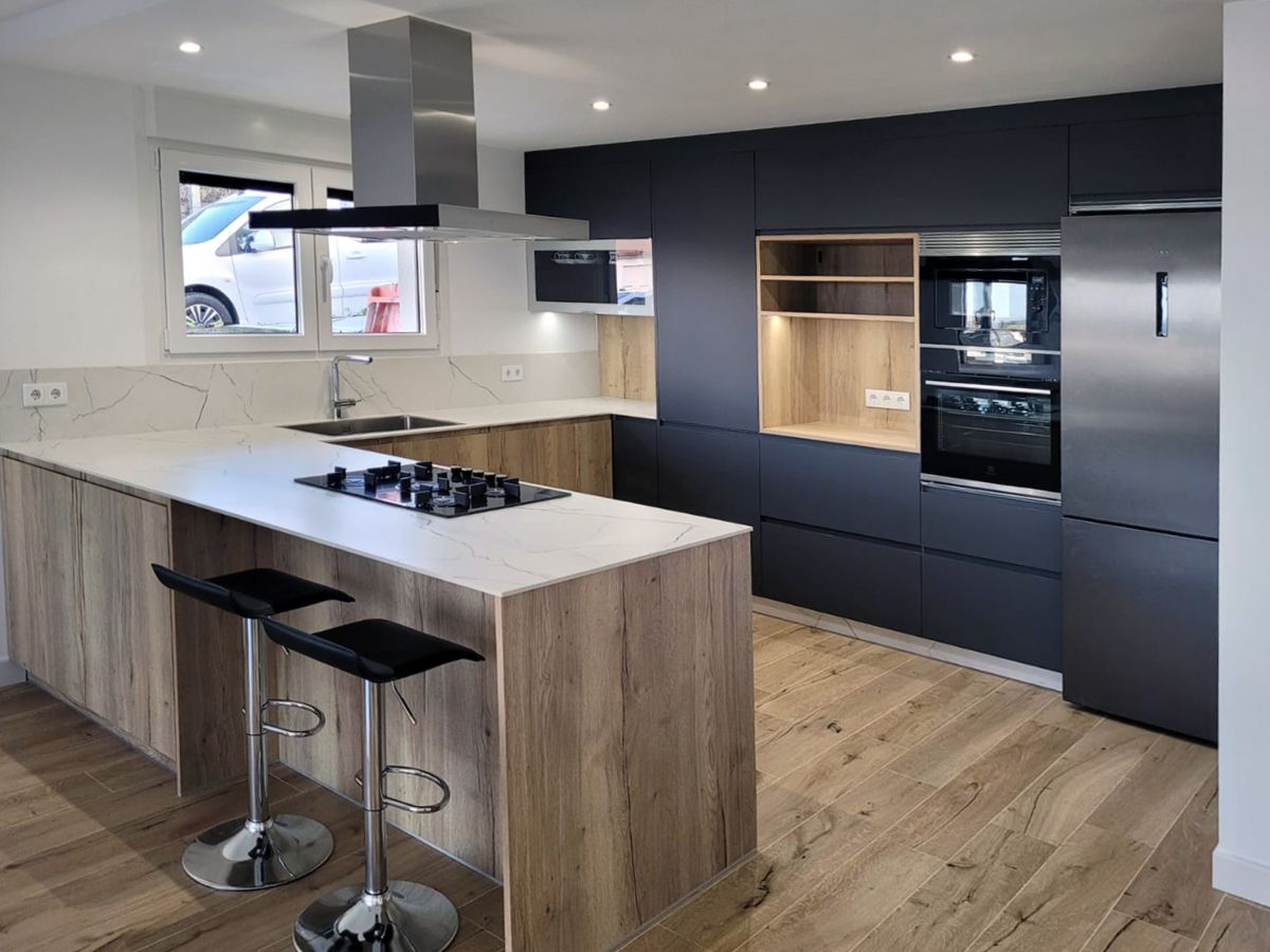 Cozinha grande com móveis em madeira e preto, electrodomésticos integrados e exaustor grande.