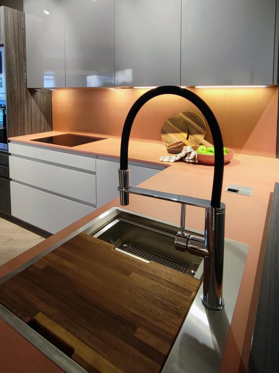 Pormenor do lava-loiça na cozinha modelo Fussion da Senssia com bancada Dekton Umbra em cor terracota, torneira moderna em acabamento preto e tábua de cortar integrada.